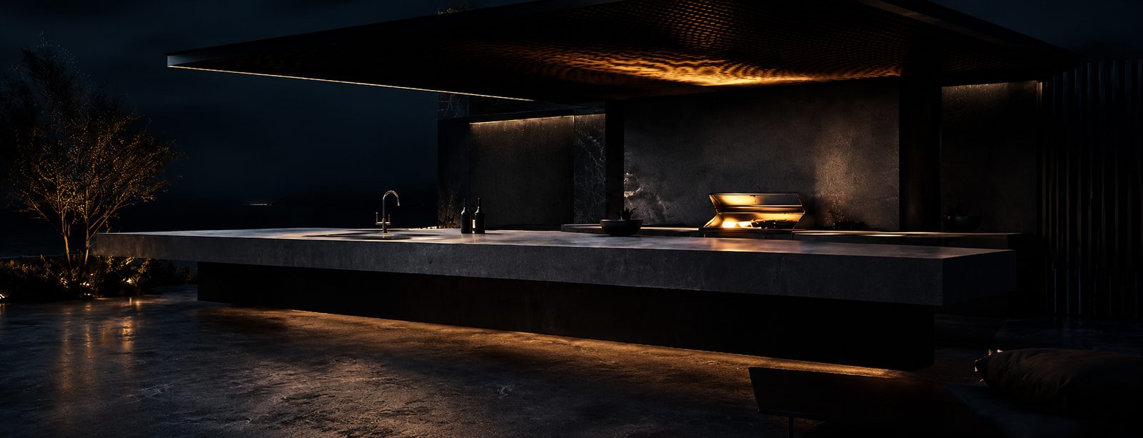 Modern outdoor kitchen at night: a monolithic stone counter with a dramatic cantilevered overhang, lit by warm under-counter and canopy lighting